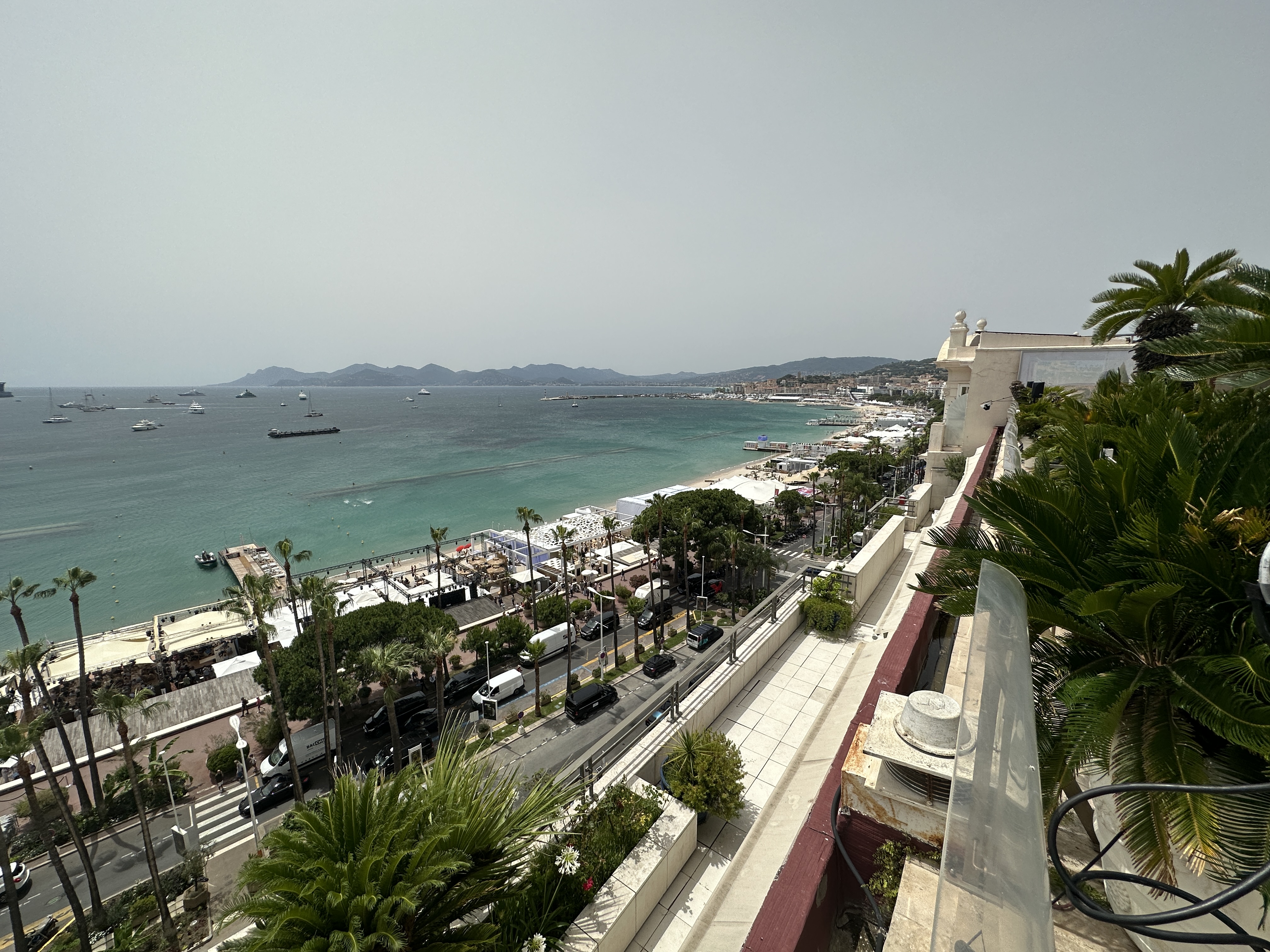 View from Le Rooftop on the Croisette, looking along the bay at Cannes with the Palais, yachts in the harbour, and the Esterel mountains in the distance